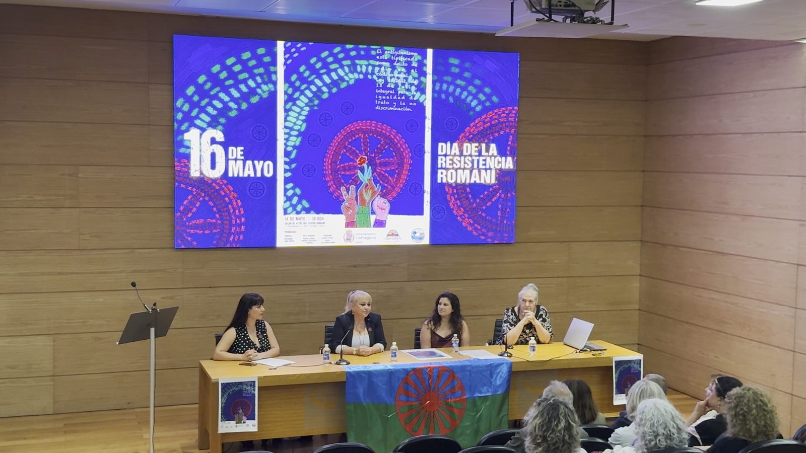 Masa rotundă, sub afișul zilei de 16 mai și cu steagul rom pe masă.